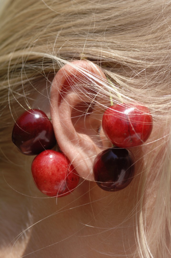 Girl wearing cherries on ear, close-up