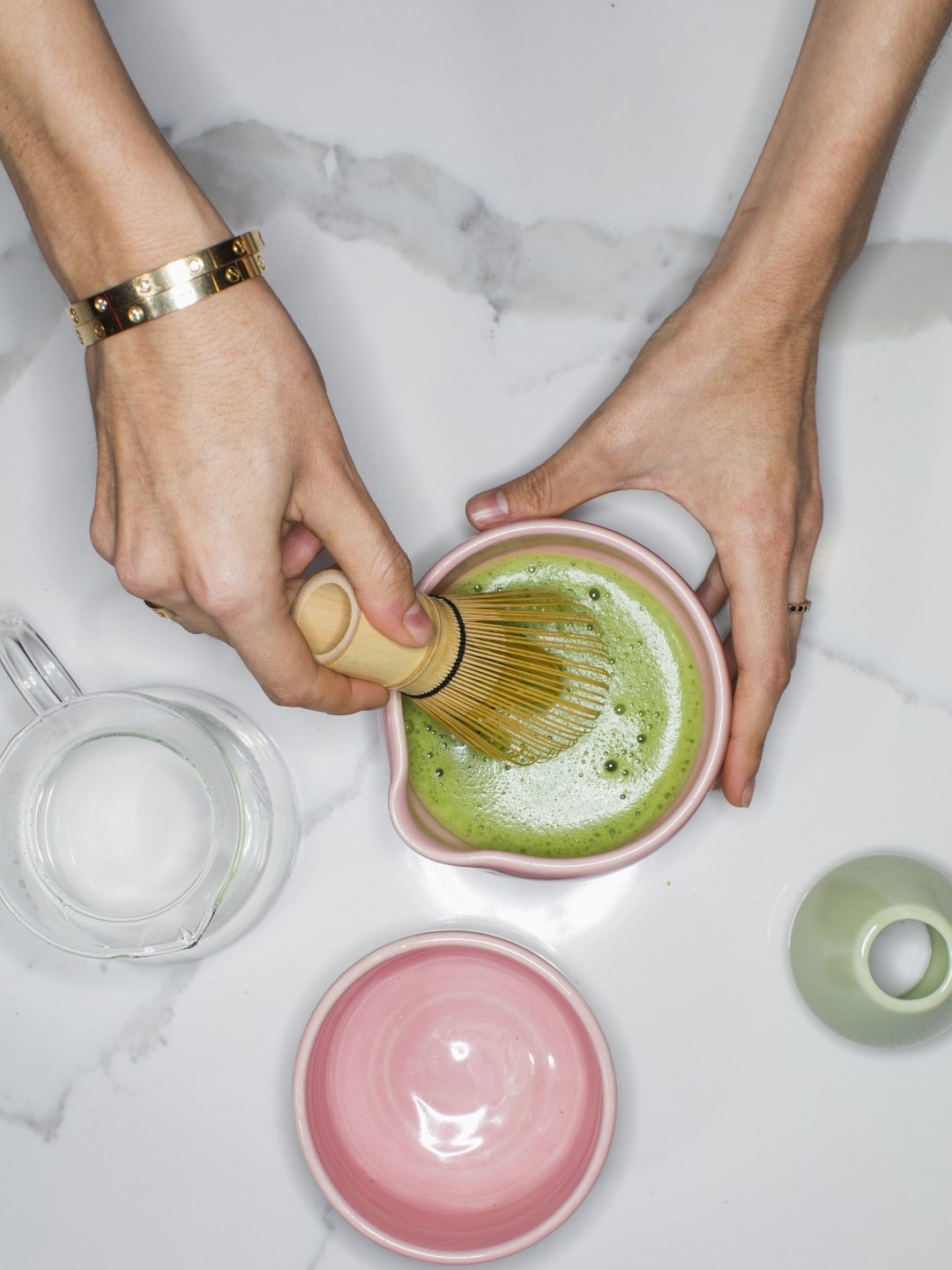 A person prepares green tea matcha in colorful pink bowl 