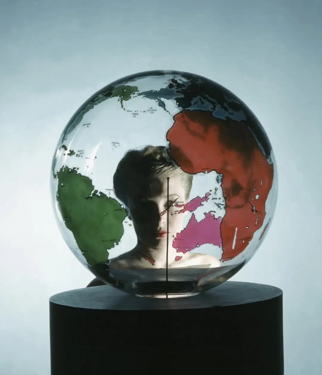 Model Susann Shaw, seen through a clear glass Earth globe on a cylindrical black pedestal, at New York's Museum of Modern Art. *** Local Caption *** Susann Shaw;