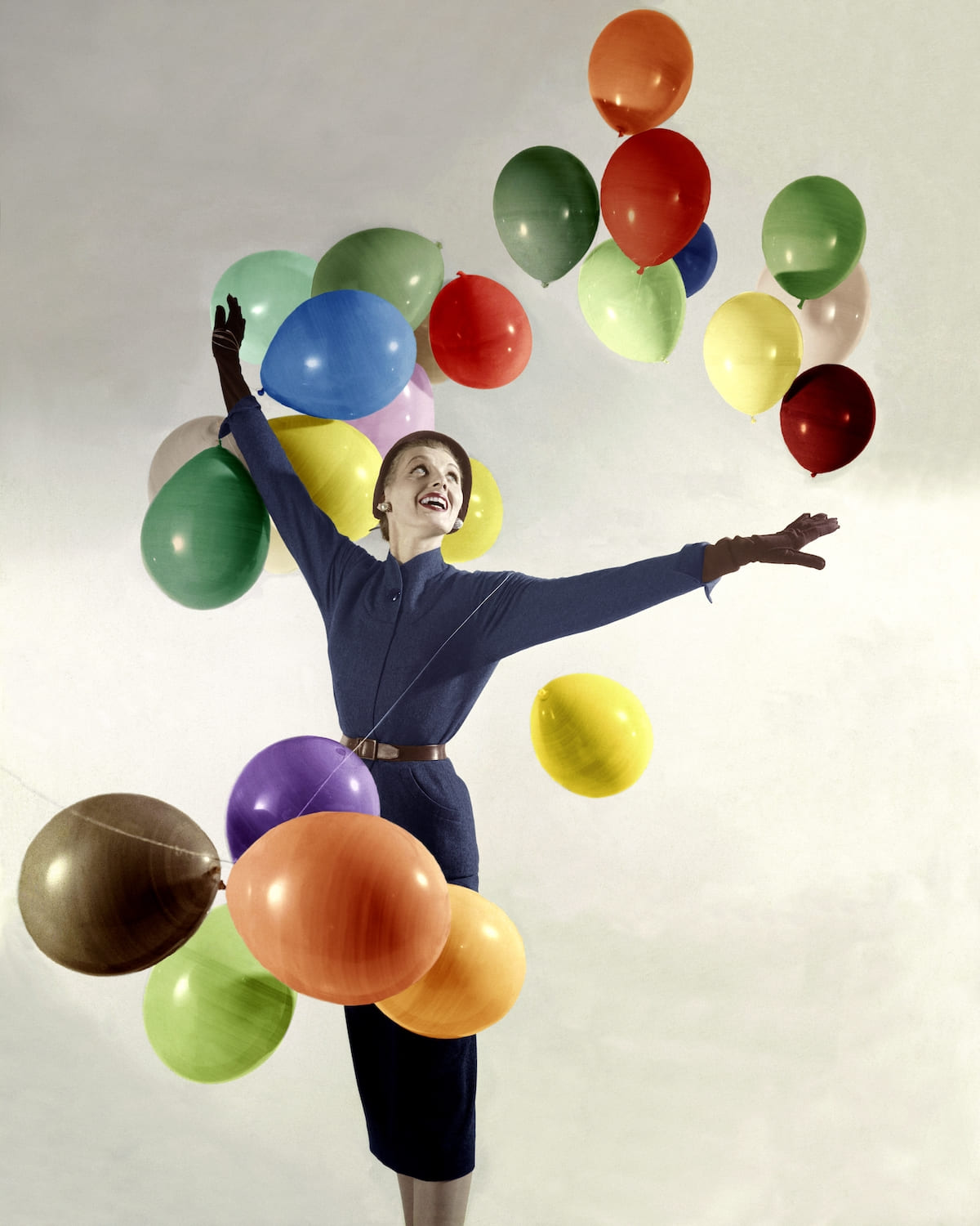 A gray-clad, hatted woman with 24 balloons of HG's new signature colors *** Local Caption ***