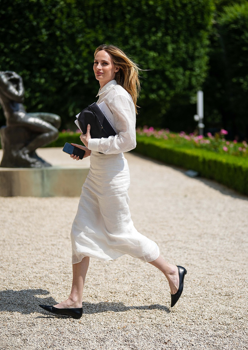 PARIS, FRANCE - JULY 03: A guest wears a white latte linen shirt, a white linen matching midi skirt, a black shiny leather clutch, black shiny leather pointed ballerinas , outside Dior , during the Haute Couture Fall/Winter 2023/2024 as part of Paris Fashion Week on July 03, 2023 in Paris, France. (Photo by Edward Berthelot/Getty Images)