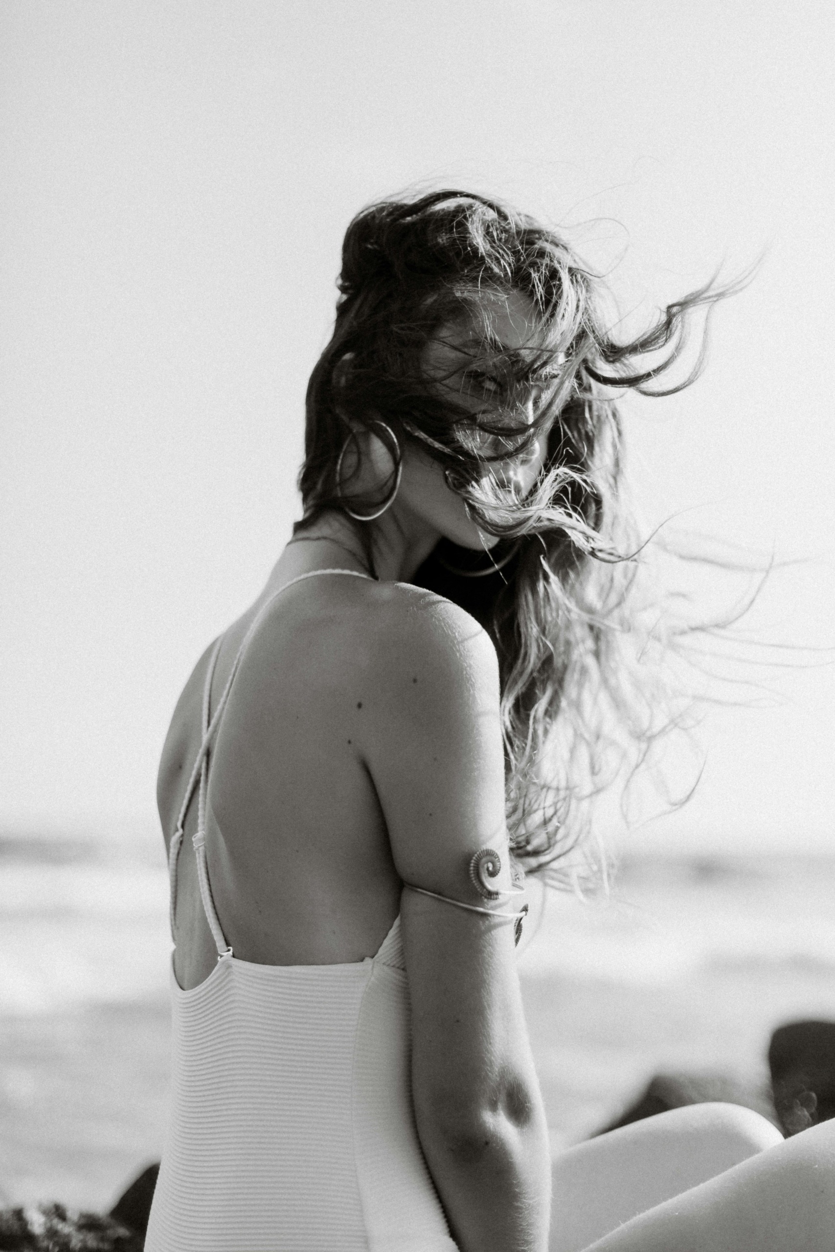 model s vjetrom u kosi sjedi na plaži