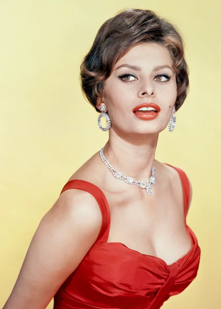 Actress Sophia Loren, seated by a mirror in a wood-paneled room, packing a wig in a leather-topped canvas hat box by Fendi. *** Local Caption *** Sophia Loren; Vogue April 15, 1972 Portrait