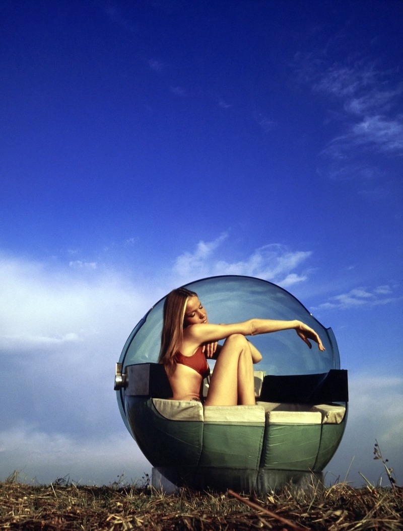 Model Veruschka sits inside of a green Plexiglass "Monade" sphere chair designed by Gianfranco Fini for Ditta Zanotta placed on a field under a blue sky. The interior is lined in white leather cushions and wired for stereo, but also includes a telephone, light, ashtrays, and a bar. Veruschka is wearing a red bikini top and a silver chain belt with Frances Denney Dew-Tan Moisturizing After Sun Lotion.Model Veruschka sits inside of a green Plexiglass "Monade" sphere chair designed by Gianfranco Fini for Ditta Zanotta placed on a field under a blue sky. The interior is lined in white leather cushions and wired for stereo, but also includes a telephone, light, ashtrays, and a bar. Veruschka is wearing a red bikini top and a silver chain belt with Frances Denney Dew-Tan Moisturizing After Sun Lotion. Model Veruschka sits inside of a green Plexiglass "Monade" sphere chair designed by Gianfranco Fini for Ditta Zanotta placed on a field under a blue sky. The interior is lined in white leather cushions and wired for stereo, but also includes a telephone, light, ashtrays, and a bar. Veruschka is wearing a red bikini top and a silver chain belt with Frances Denney Dew-Tan Moisturizing After Sun Lotion. Vogue September 15, 1969 Portrait