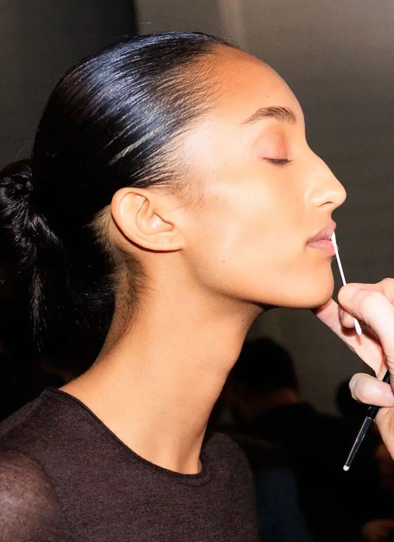 vizažist nanosi ruž na usne modela u backstageu