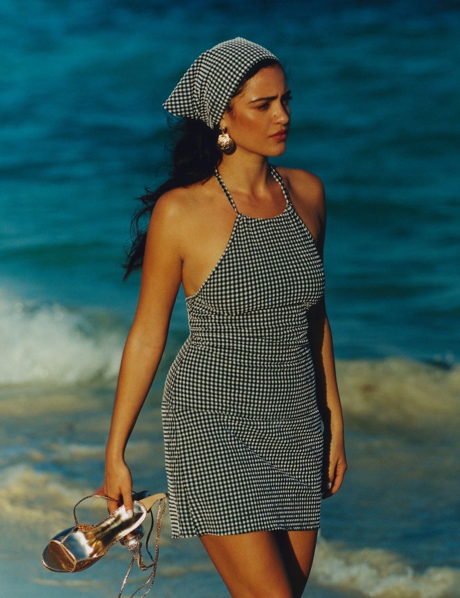 model s preplanulom kožom šeta na plaži u haljini i s maramom na glavi