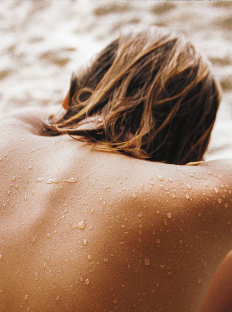žena se sunča na plaži s mokrom kosom