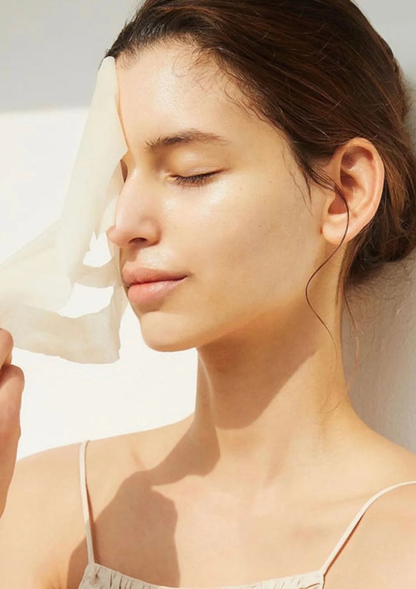 žena skida sheet masku s lica i uživa u suncu