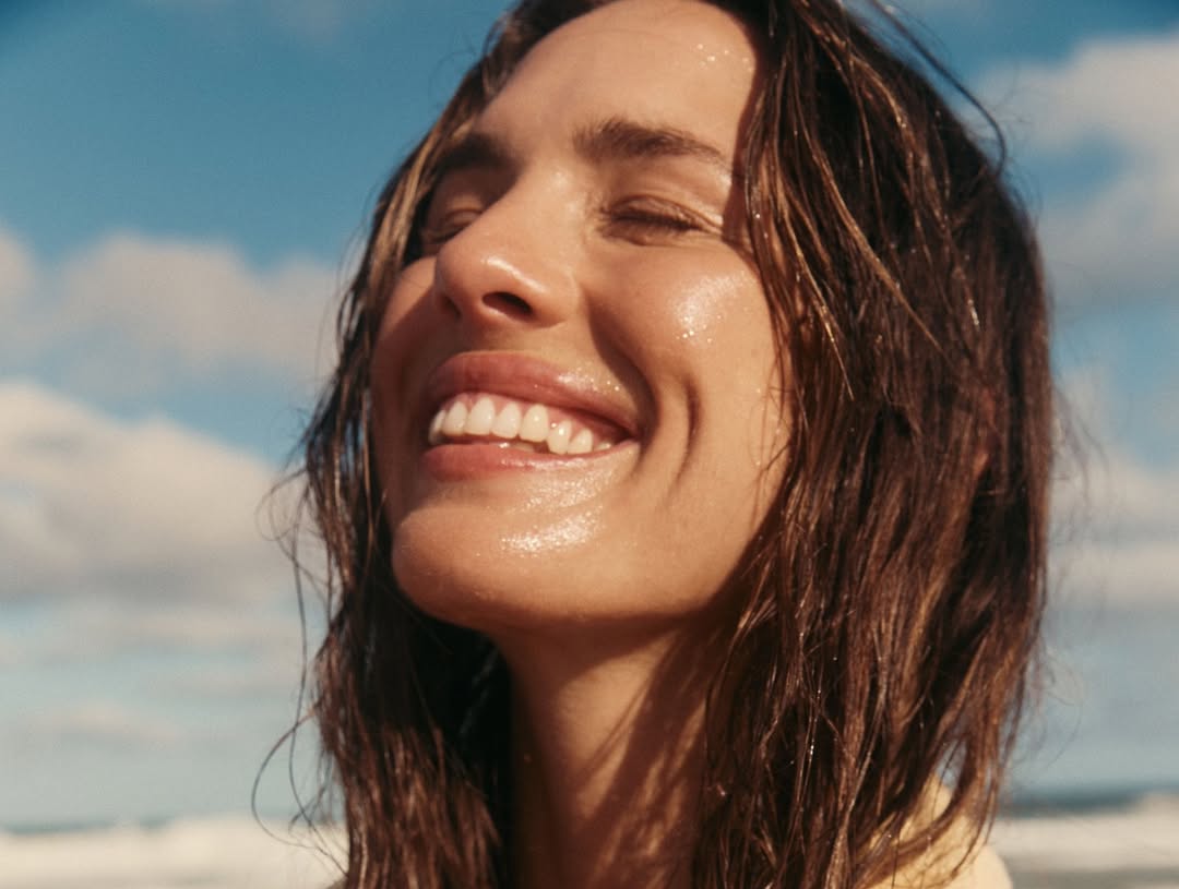žena s blistavom kožom se smije na plaži