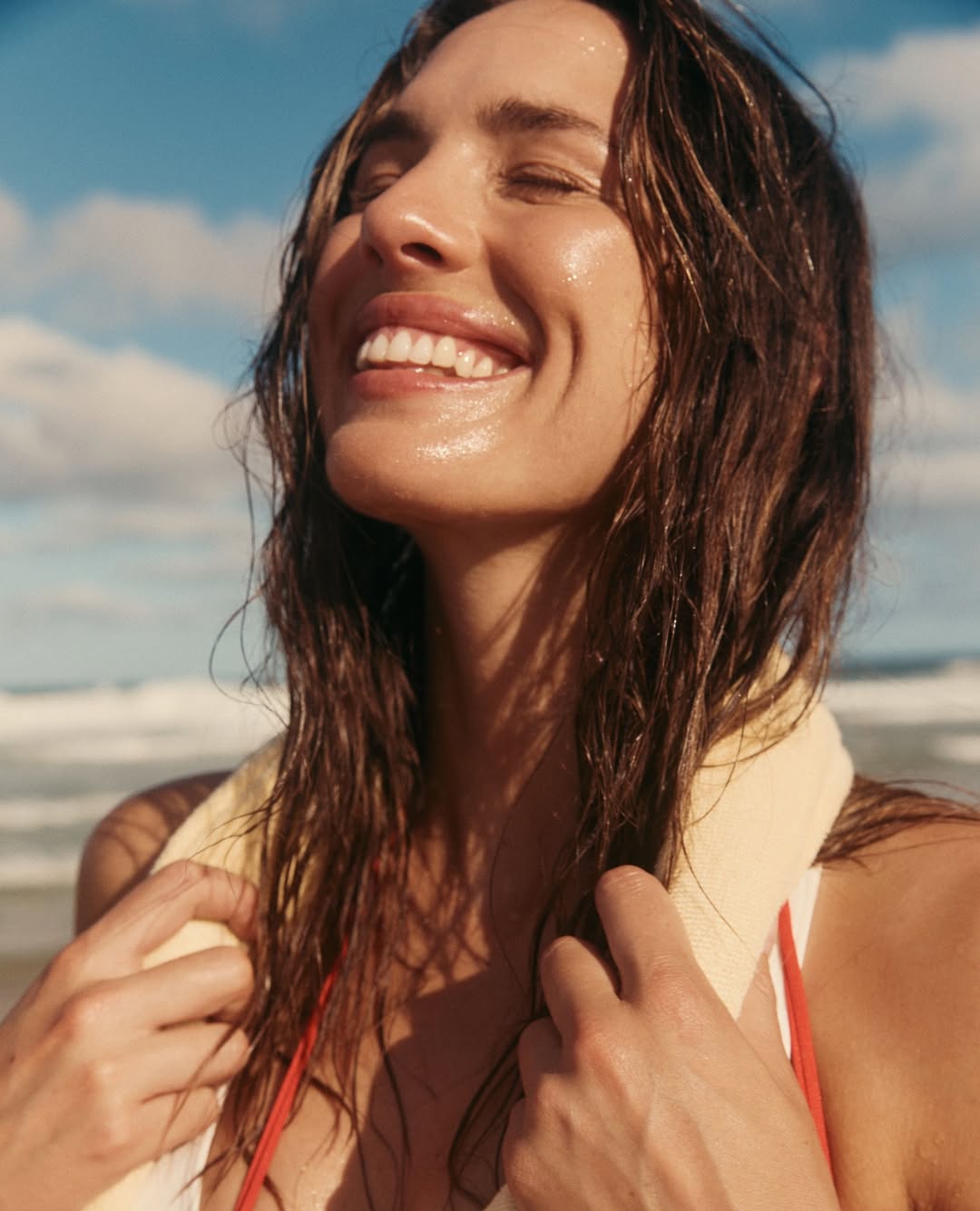 žena s blistavom kožom se smije na plaži nakon kupanja