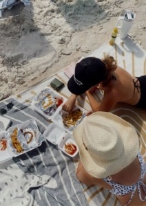 dvije djevojke leže na plaži i jedu fast food