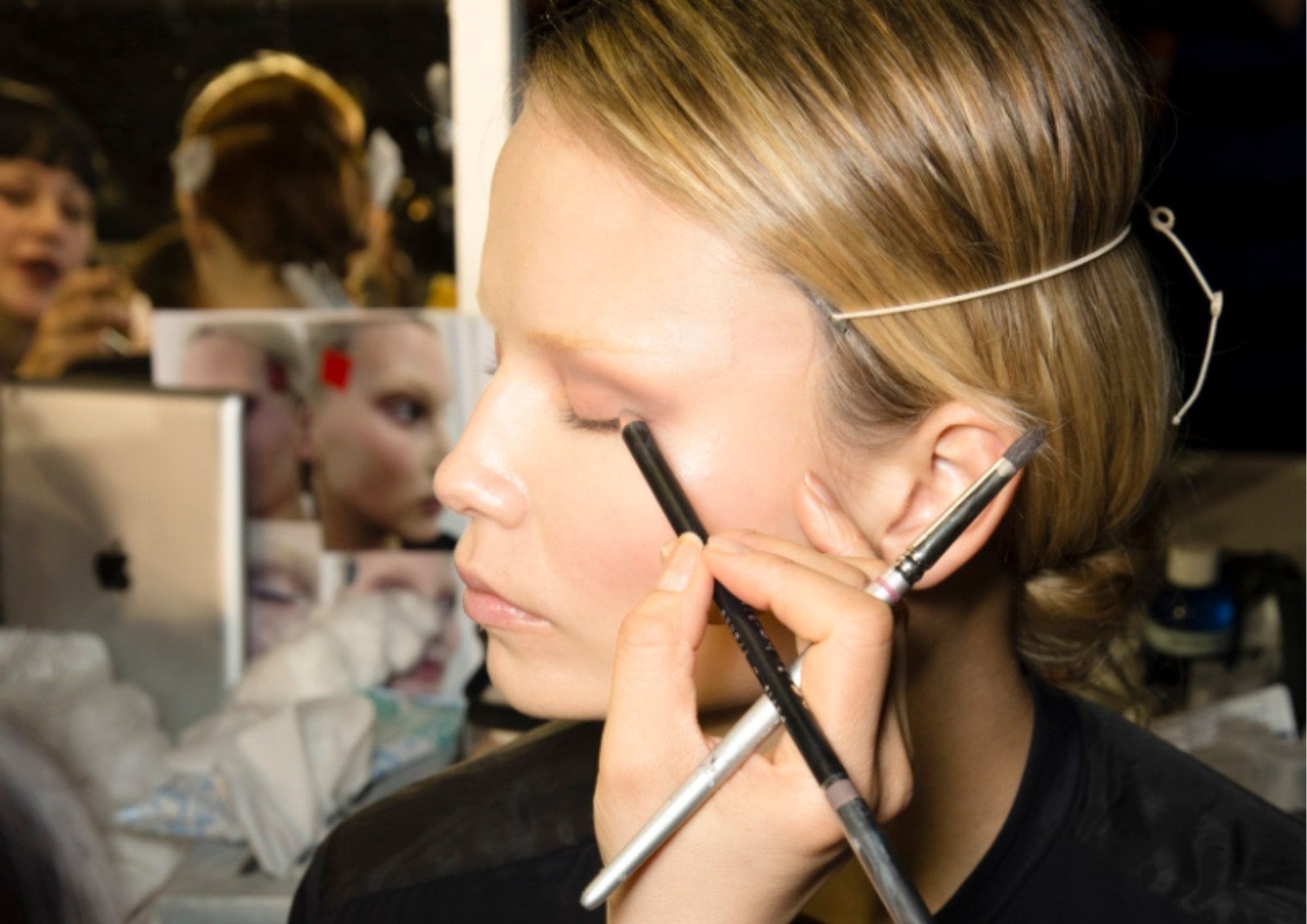 vizažistica nanosi olovku za oči na lice modela u backstageu