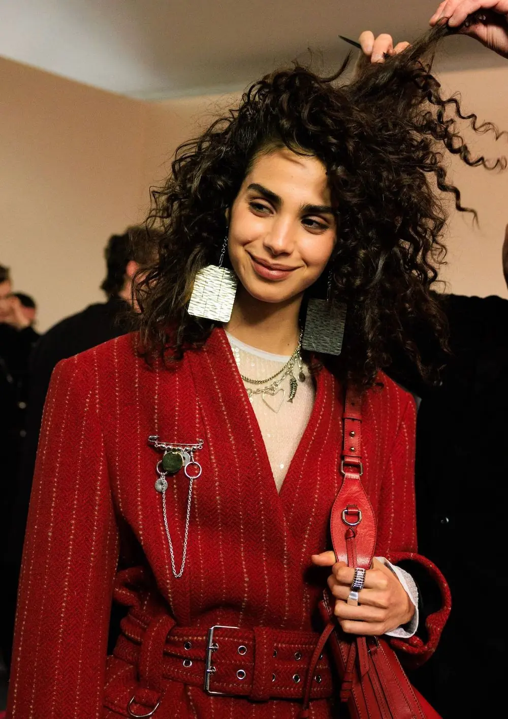 djevojka s nahranjenom i sjajnom, kovrčavom kosom u crvenoj jakni