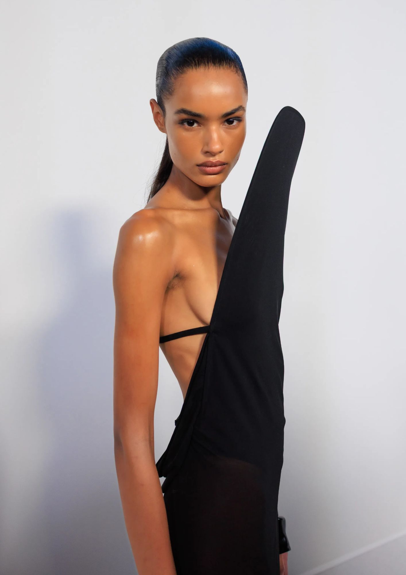 model sa sjajnom kožom i ujednačenim tenom u crnoj haljini