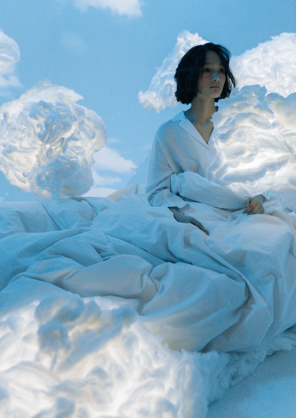 žena u bijeloj odjeći sjedi u sobi s mekanim oblacima dok se opušta protiv stresa