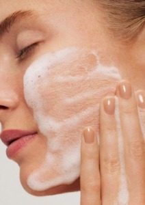 ženska si čisti obraz z vlažilno peno