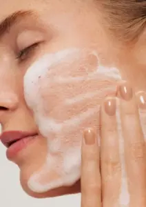 žena čisti lice s hidratantnom pjenom