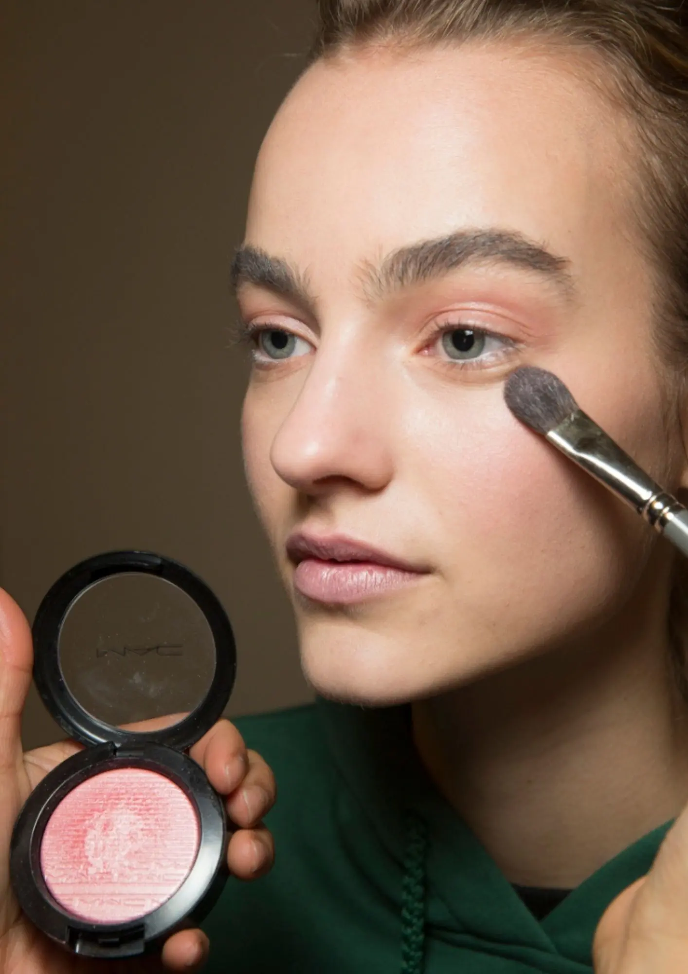 vizažistica nanosi hot pink rumenilo na obraze modela prije revije