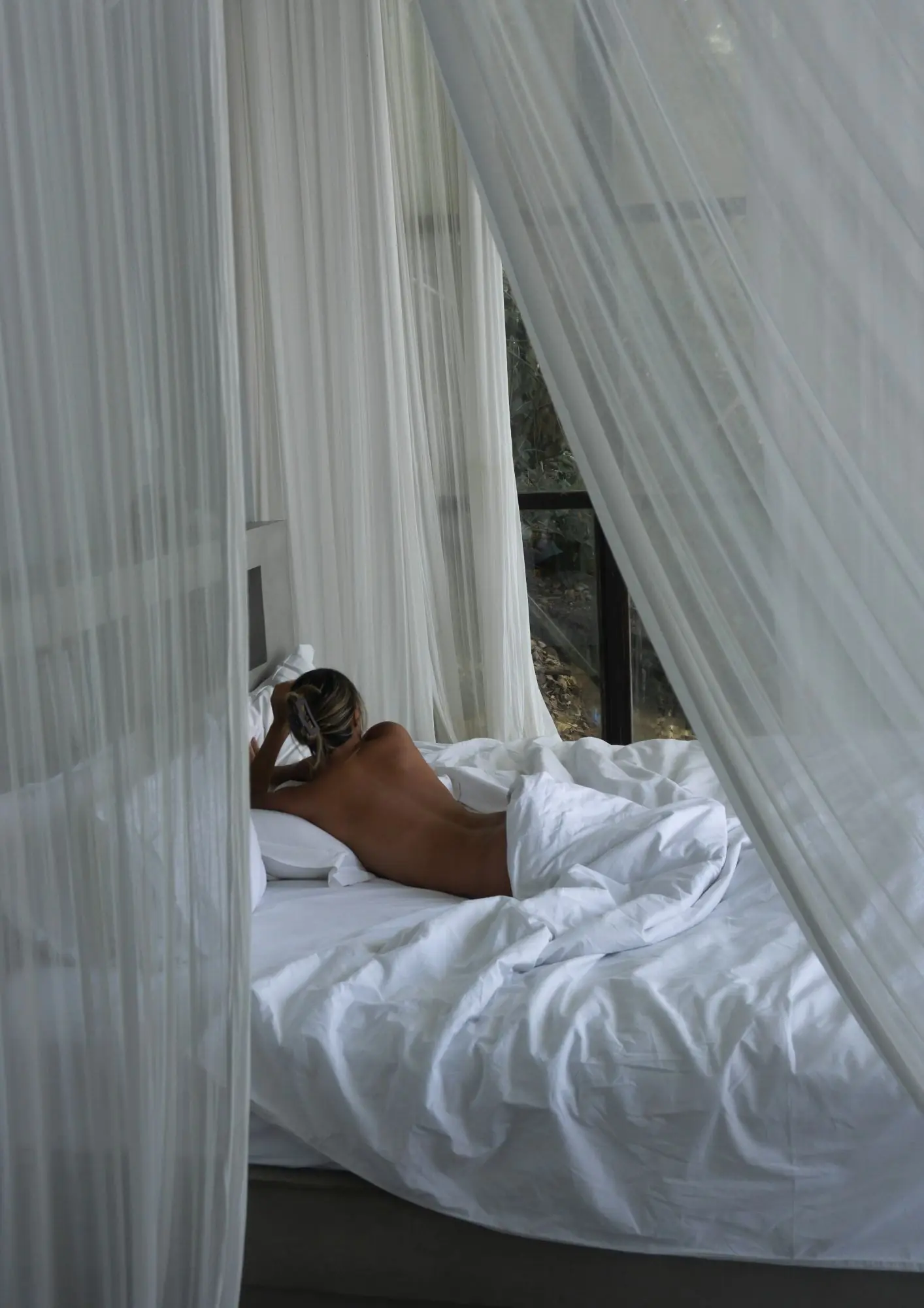 žena leži u krevetu s bijelom posteljinom