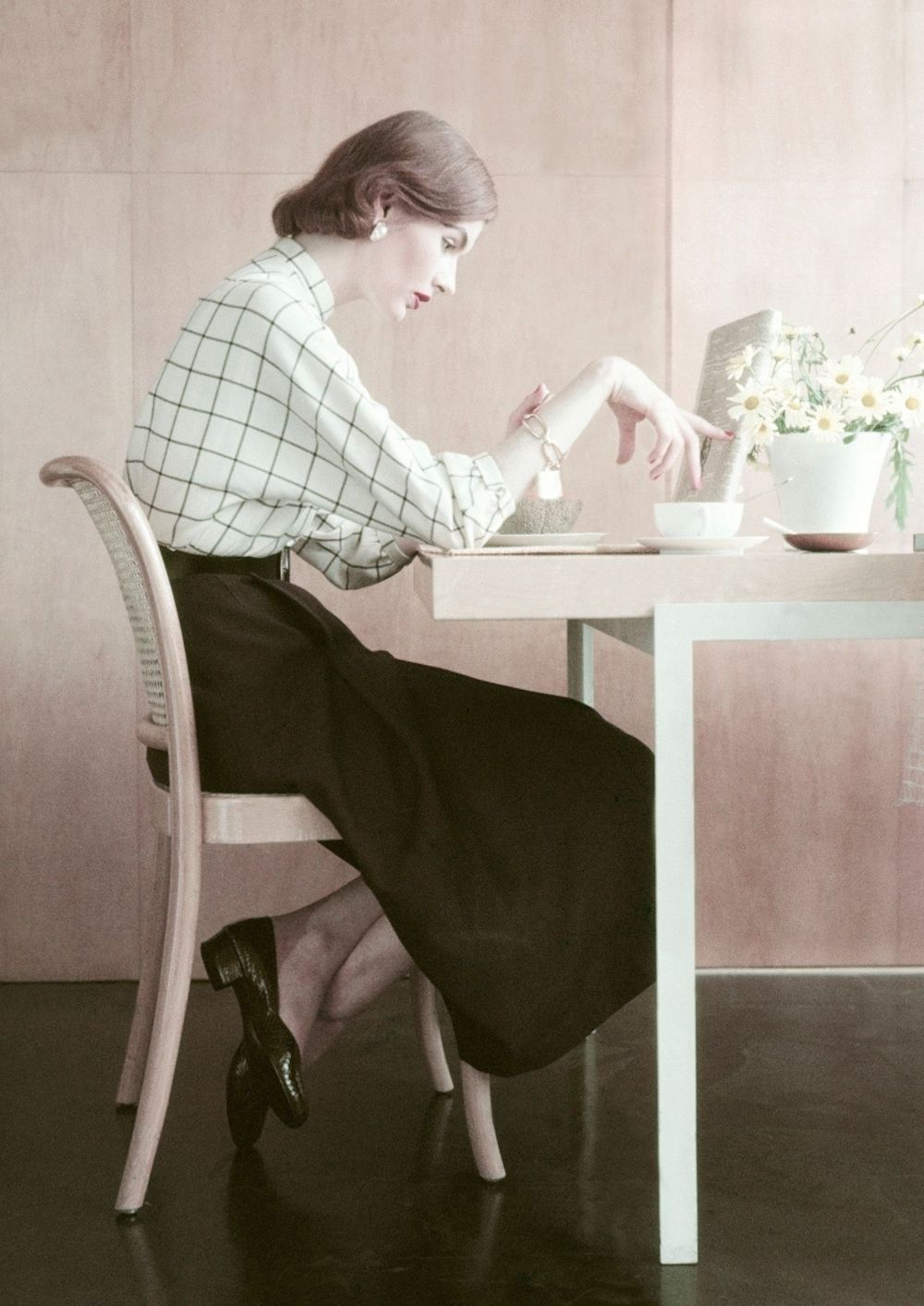 žena u bijeloj košulju i crnoj suknji sjedi za stolom pod stresom