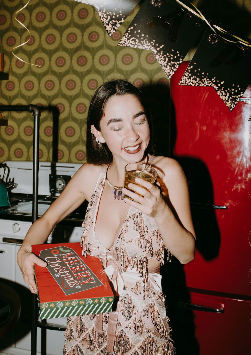 žena na blagdanskoj zabavi drži čašu s pićem i poklon kutiju