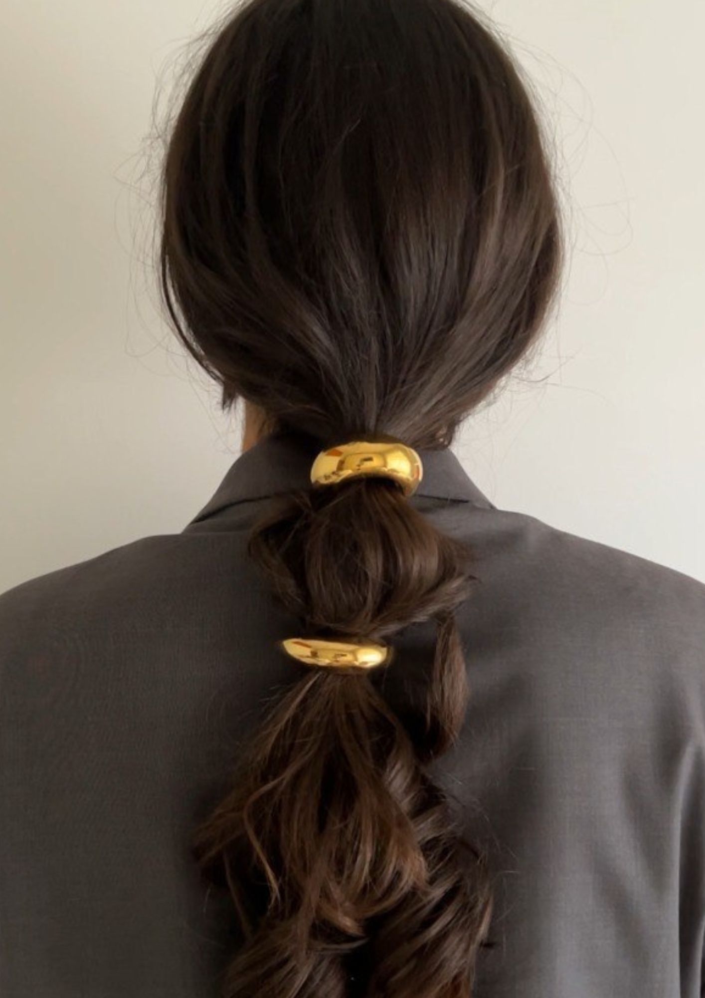 model sa smeđom kosom zavezanom u rep sa zlatnim kopčama